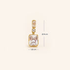 A pair of gold drop earrings featuring rectangular clear crystals in gold bezel settings, accented with small round clear stones, shown on a light cream background with size.