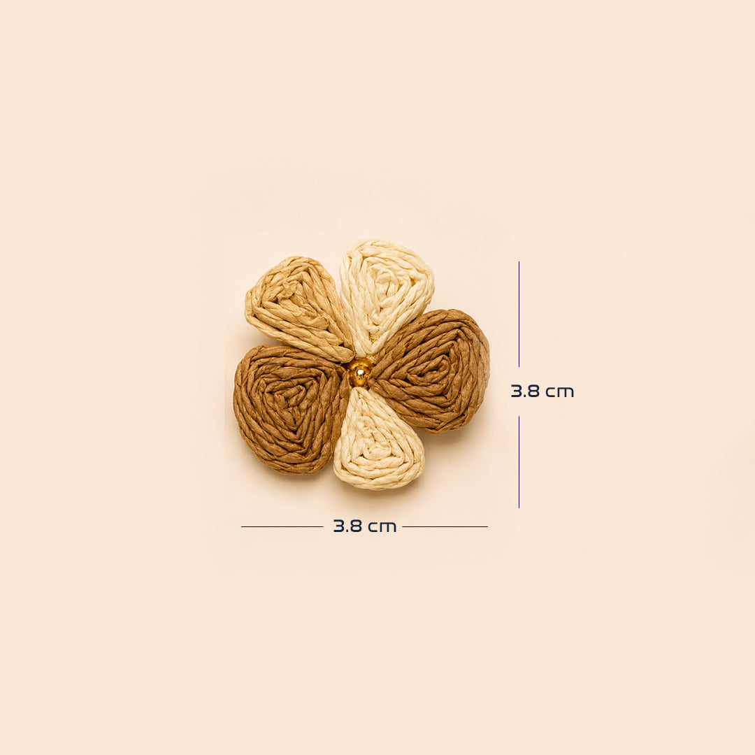 A woven flower-shaped hair accessory in three shades of brown and beige, shown with dimension lines indicating a width and height of 3.8 cm on a solid beige background.