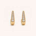 A pair of gold huggie  earrings, each adorned with a vertical row of round-cut clear gemstones, set against a clean off-white background.