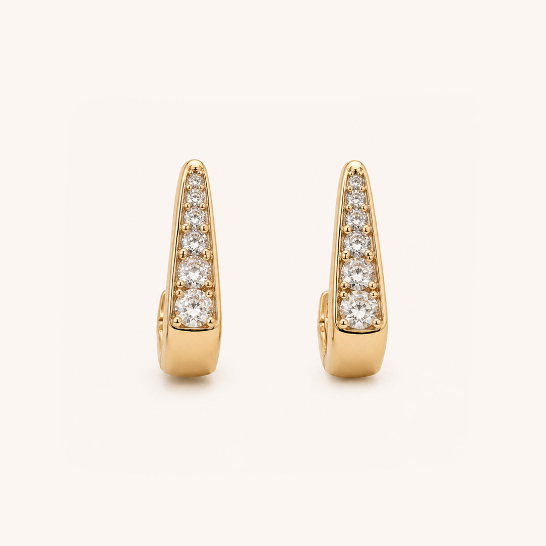 A pair of gold huggie  earrings, each adorned with a vertical row of round-cut clear gemstones, set against a clean off-white background.