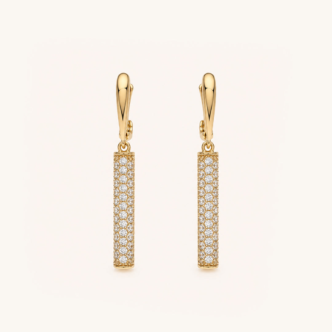 A pair of gold leverback drop earrings with vertical pavé columns of clear stones, shown on a clean off-white background.