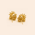 A pair of gold stud earrings with a textured, organic leaf-like design and small flower-like tops, displayed on a solid light beige background.