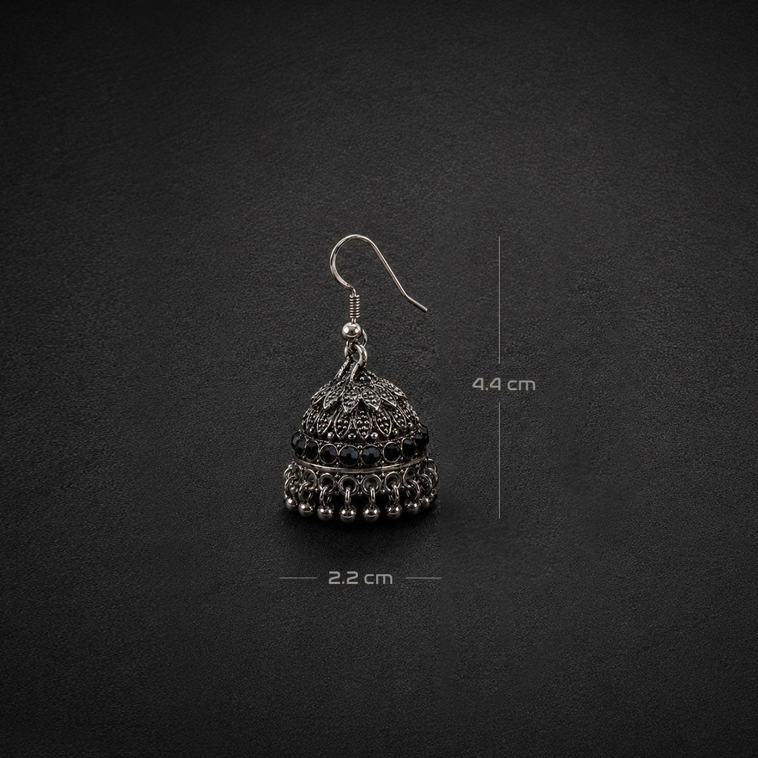 A single silver-toned jhumka earring with black oxidized detailing, shown on a dark textured background with dimension markers indicating 4.4 cm height and 2.