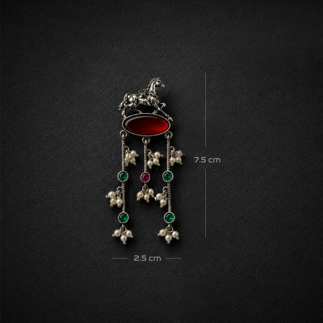 A silver-toned traditional Indian pendant featuring a horse motif, a red oval stone, and three dangling floral clusters with green and red stones and pearl-like beads. Measurement annotations indicate 7.