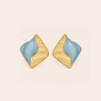 A pair of  light blue geometric stud earrings on a golden background.
